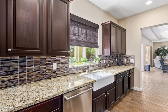 kitchen with dishwasher, light stone counters, sink, dark brown cabinets, and tasteful backsplash