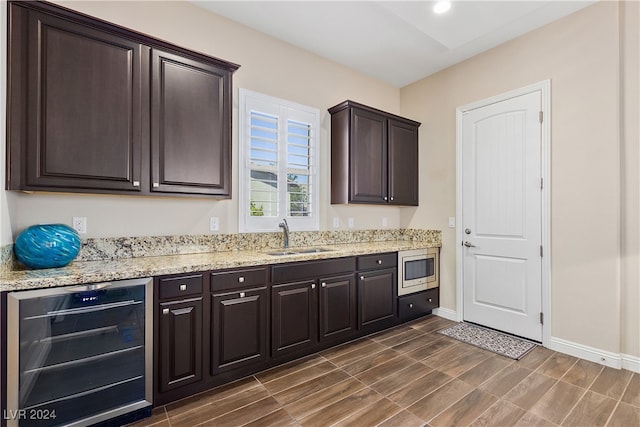 kitchen featuring stainless steel microwave, dark brown cabinetry, wine cooler, and sink