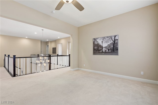 empty room featuring ceiling fan with notable chandelier and light carpet