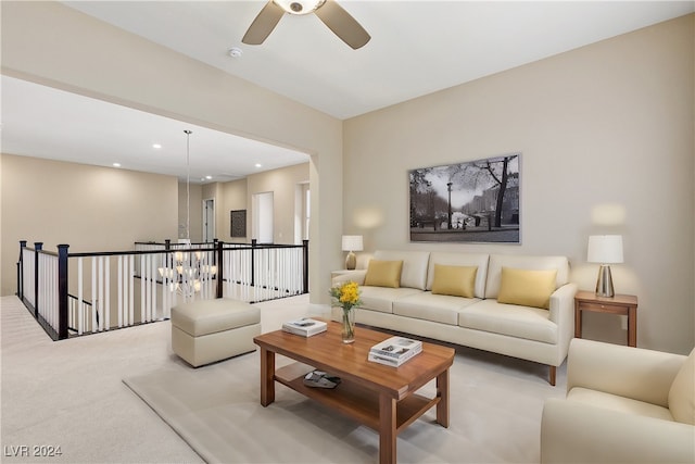 living room featuring ceiling fan with notable chandelier and light carpet