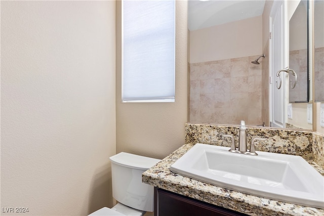 bathroom with tiled shower, vanity, and toilet