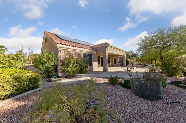 back of property featuring a patio and solar panels