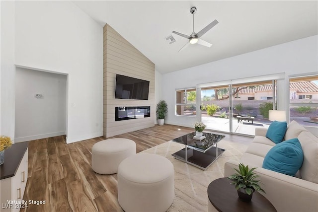 living room with ceiling fan, wood-type flooring, a fireplace, and high vaulted ceiling