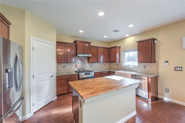 kitchen with butcher block countertops, dark hardwood / wood-style floors, appliances with stainless steel finishes, and a kitchen island