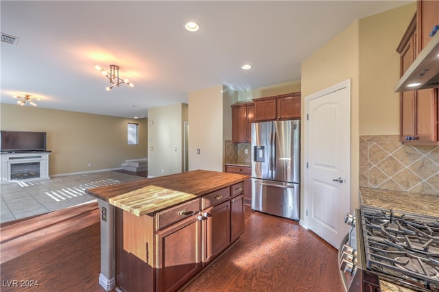 kitchen featuring stainless steel appliances, backsplash, wood counters, a center island, and dark hardwood / wood-style flooring