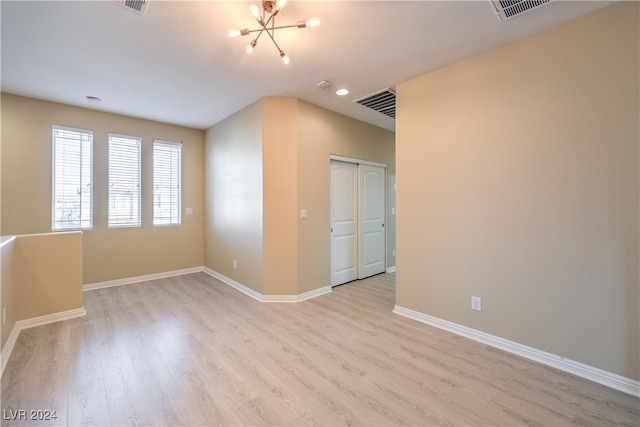 unfurnished room with an inviting chandelier and light wood-type flooring