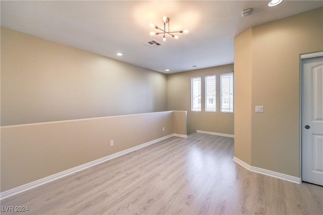 unfurnished room with light hardwood / wood-style flooring and an inviting chandelier