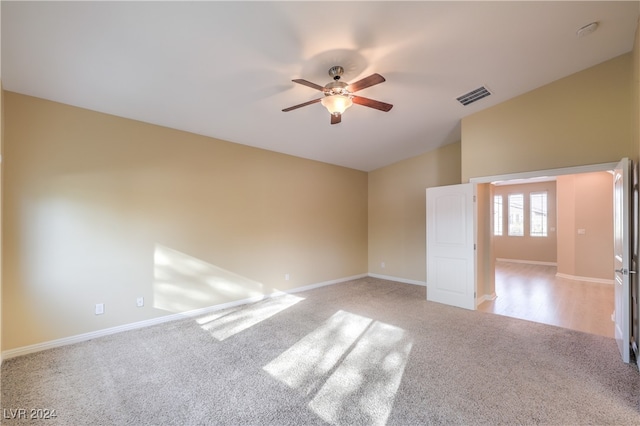 empty room featuring light carpet, vaulted ceiling, and ceiling fan