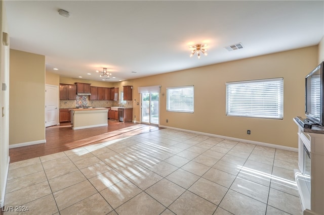 unfurnished living room with a chandelier and light tile patterned floors