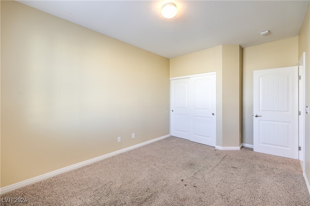 unfurnished bedroom featuring light carpet and a closet