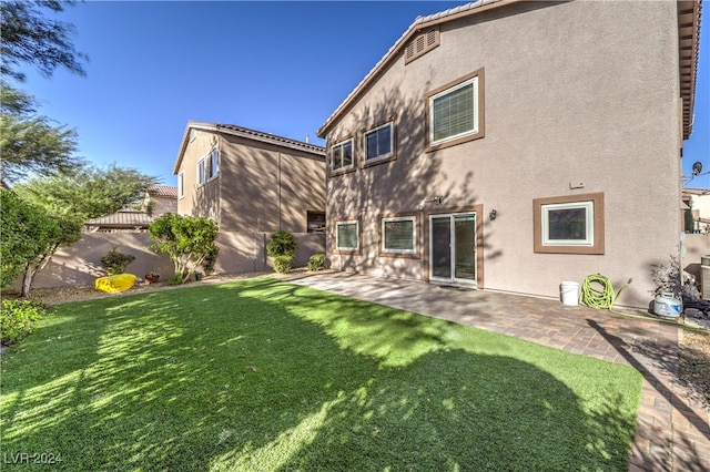 rear view of house featuring a patio and a lawn