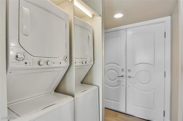 laundry room with stacked washer and clothes dryer and light wood-type flooring