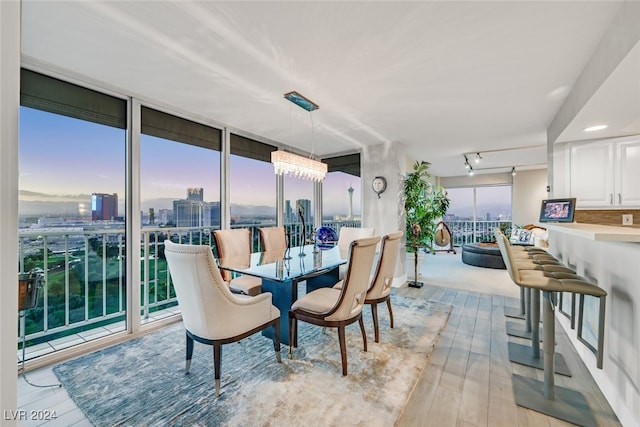 dining space featuring light hardwood / wood-style floors, expansive windows, and an inviting chandelier