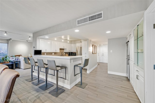 3111 Bel Air Dr Unit 25A, Las Vegas, NV 89109 - kitchen with freestanding refrigerator, a peninsula, a kitchen bar, light wood-style floors, and open floor plan