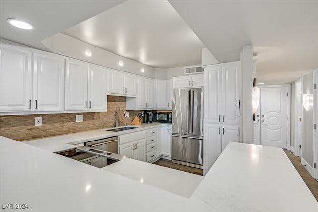 kitchen with dark hardwood / wood-style flooring, backsplash, white cabinetry, sink, and stainless steel appliances