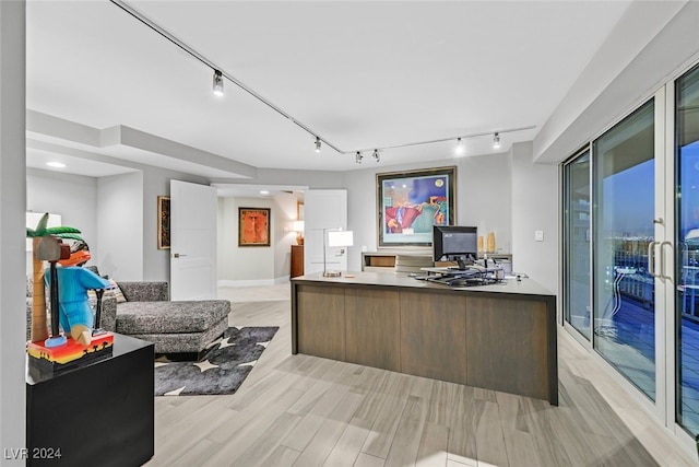 home office with light hardwood / wood-style floors and rail lighting