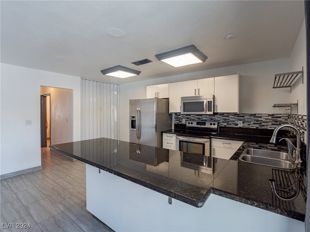 kitchen with white cabinets, stainless steel appliances, a breakfast bar area, and sink