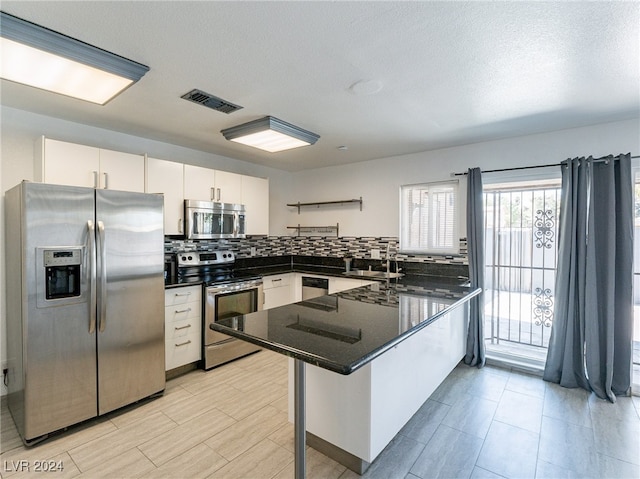 kitchen featuring white cabinetry, stainless steel appliances, tasteful backsplash, a kitchen breakfast bar, and kitchen peninsula