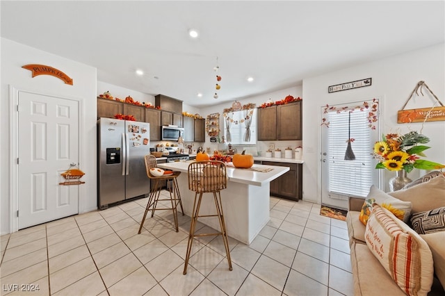 kitchen with a center island, appliances with stainless steel finishes, a kitchen bar, and plenty of natural light