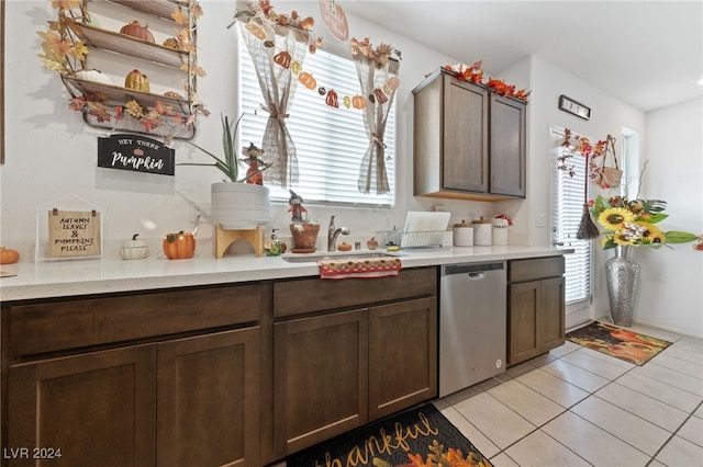 kitchen with stainless steel dishwasher, sink, dark brown cabinets, and light tile patterned floors