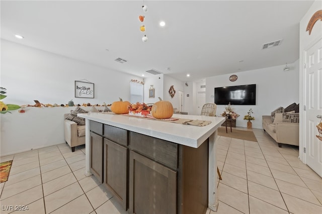 kitchen with a center island, dark brown cabinetry, and light tile patterned floors