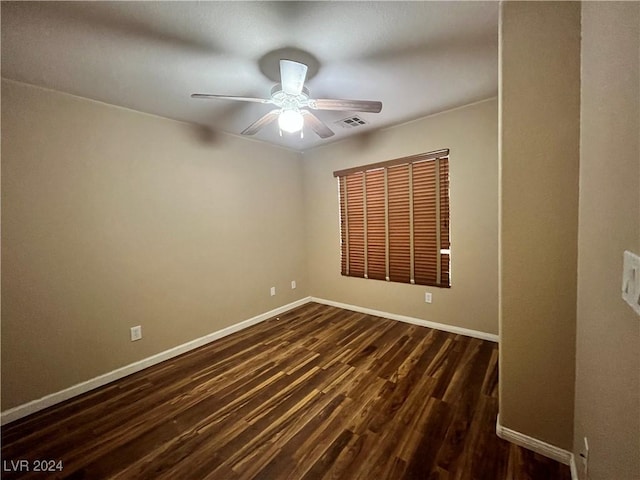 spare room with a ceiling fan, dark wood-style flooring, visible vents, and baseboards