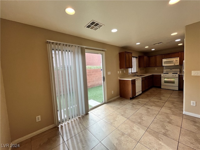 kitchen with sink, light tile patterned flooring, and white appliances