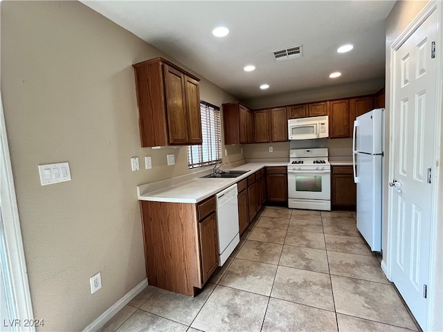 kitchen with white appliances, light tile patterned floors, and sink