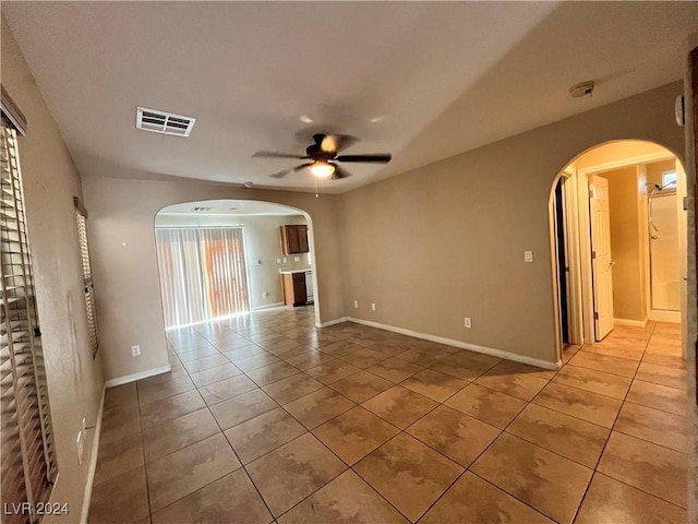 unfurnished room featuring light tile patterned floors, ceiling fan, visible vents, and arched walkways