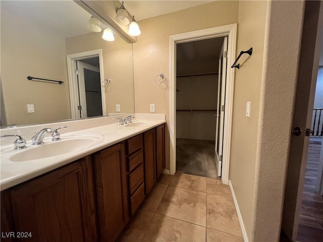 bathroom with double vanity, tile patterned flooring, a spacious closet, and a sink