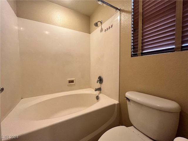 bathroom featuring a textured wall, bathing tub / shower combination, and toilet