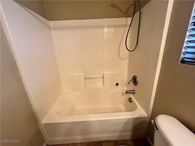 bathroom with a textured wall, shower / bathing tub combination, and toilet