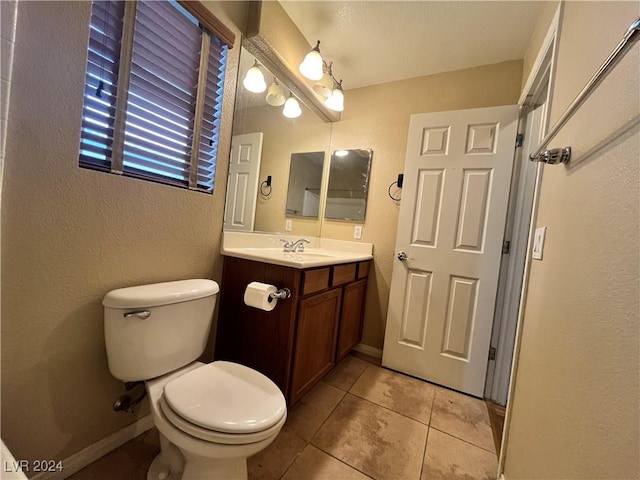 half bath featuring toilet, tile patterned flooring, vanity, and baseboards