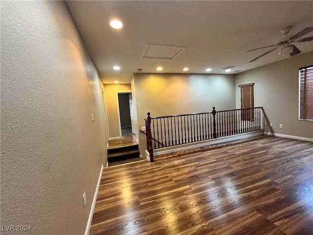 spare room featuring dark wood-type flooring, recessed lighting, attic access, and baseboards