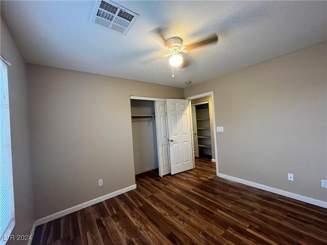 unfurnished bedroom with dark wood-style floors, a closet, visible vents, and baseboards