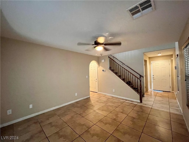 unfurnished room with light tile patterned floors, baseboards, visible vents, a ceiling fan, and stairway