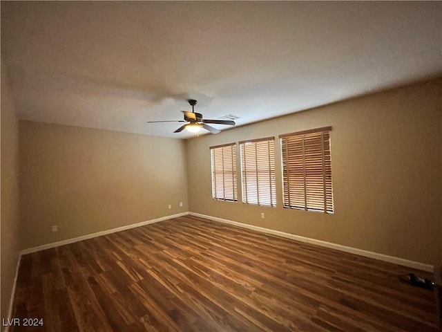 unfurnished room featuring visible vents, dark wood-type flooring, a ceiling fan, and baseboards