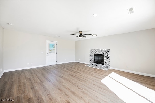 unfurnished living room with a tile fireplace, light hardwood / wood-style floors, and ceiling fan