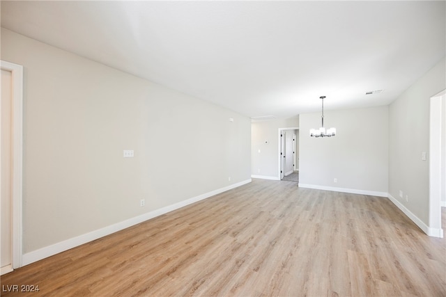 empty room featuring light wood-type flooring and a chandelier