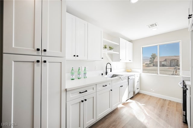 kitchen with white cabinets, stainless steel dishwasher, light wood-type flooring, and sink