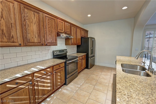 kitchen featuring light stone counters, stainless steel appliances, sink, and backsplash