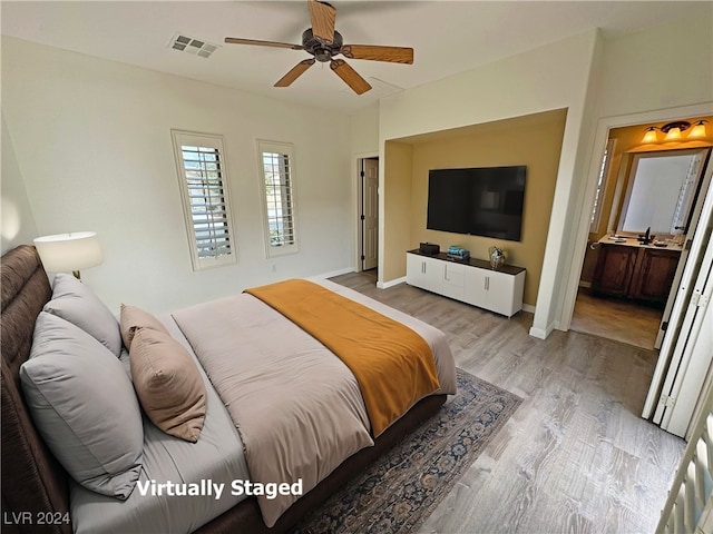 bedroom featuring connected bathroom, sink, light hardwood / wood-style flooring, and ceiling fan