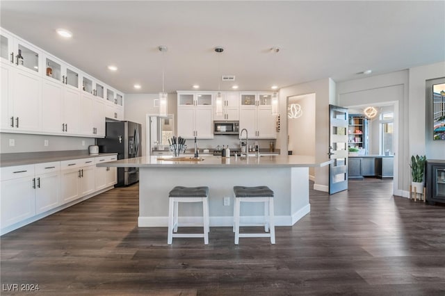 kitchen with a center island with sink, hanging light fixtures, stainless steel appliances, and dark hardwood / wood-style flooring