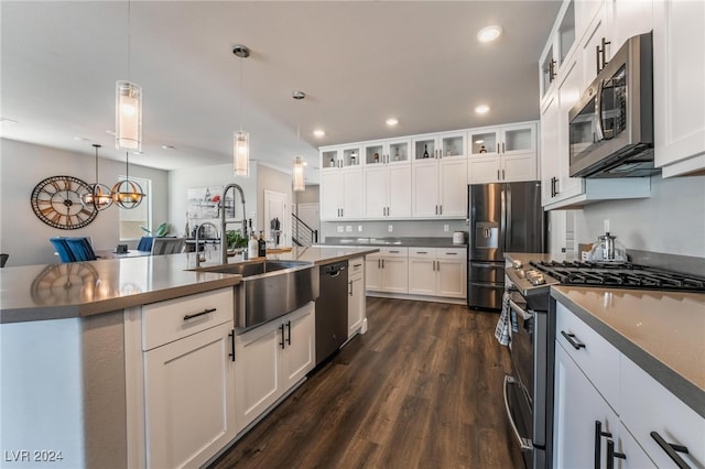 kitchen featuring stainless steel appliances, pendant lighting, white cabinets, dark wood-type flooring, and a kitchen island with sink