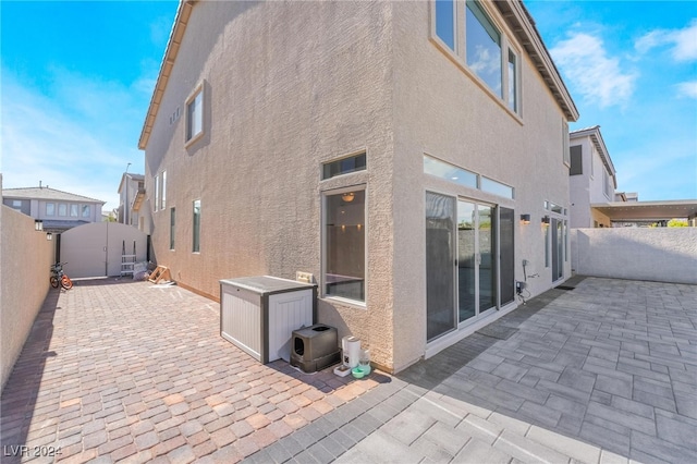 back of property featuring a shed and a patio