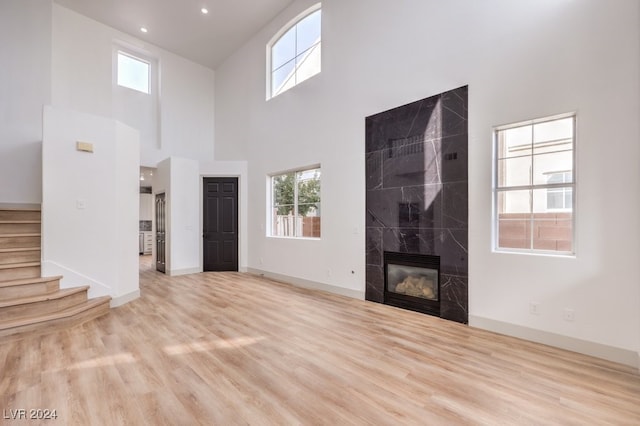 unfurnished living room with a towering ceiling, a healthy amount of sunlight, and light wood-type flooring