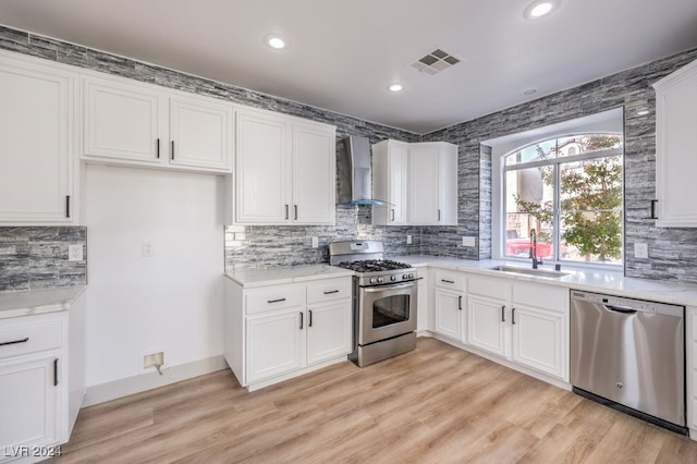 kitchen with sink, white cabinets, wall chimney range hood, and stainless steel appliances