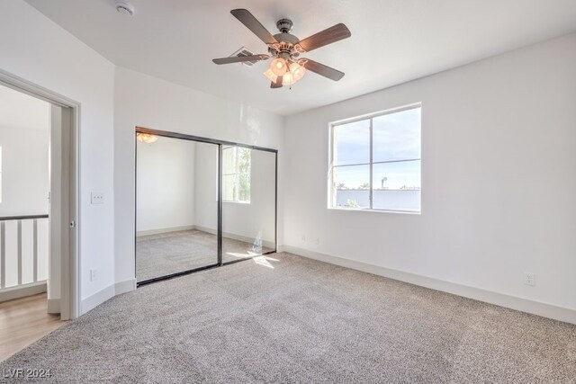 unfurnished bedroom with light colored carpet, a closet, and ceiling fan