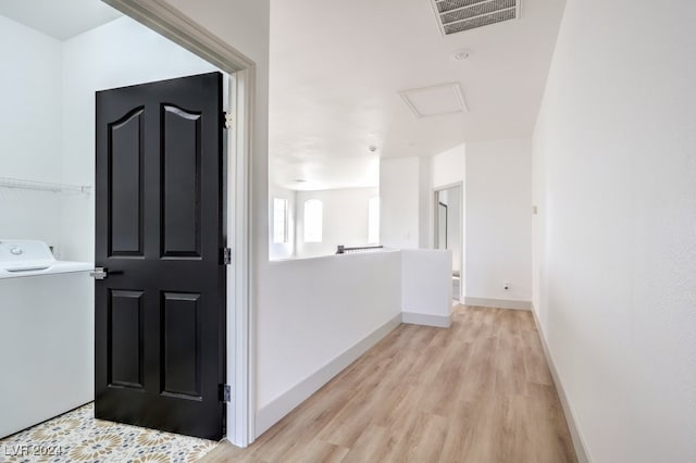 corridor with washer / dryer and light hardwood / wood-style flooring