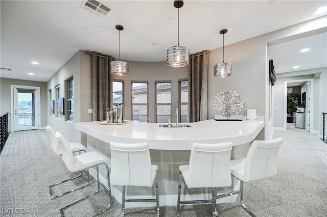 kitchen with light colored carpet and pendant lighting